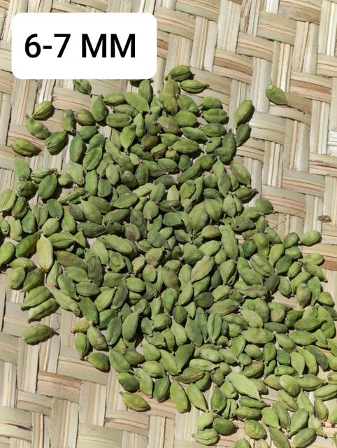 Green cardamom pods on wooden surface